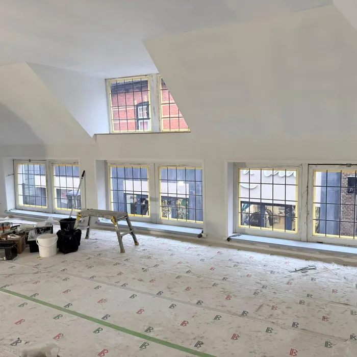 Binnenruimte tijdens renovatie aan de Grootestraat in Oldenzaal met voorbereid binnenstucwerk en afgedekte vloer voorafgaand aan schilderwerk.