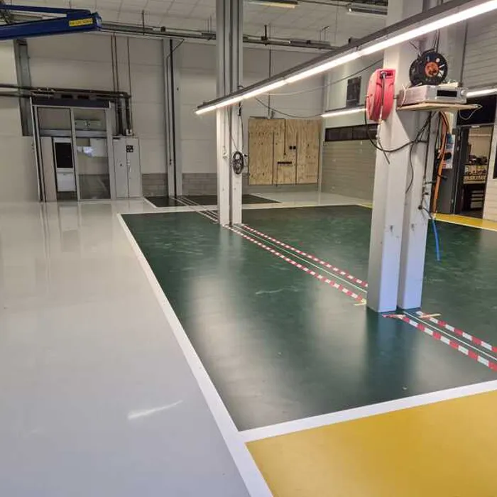 Afgewerkte epoxy vloercoating bij Grolsch met groene kleurvlakken en witte belijning