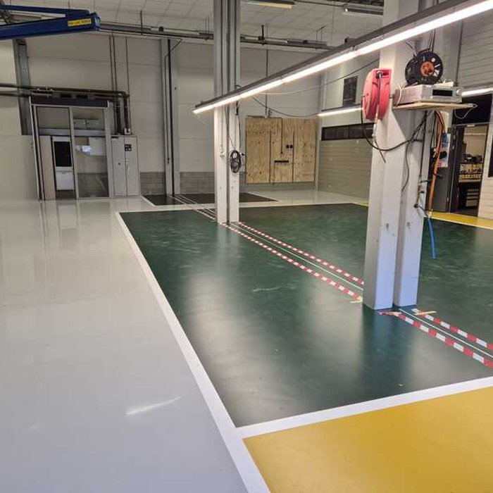 Afgewerkte epoxy vloercoating bij Grolsch met groene kleurvlakken en witte belijning