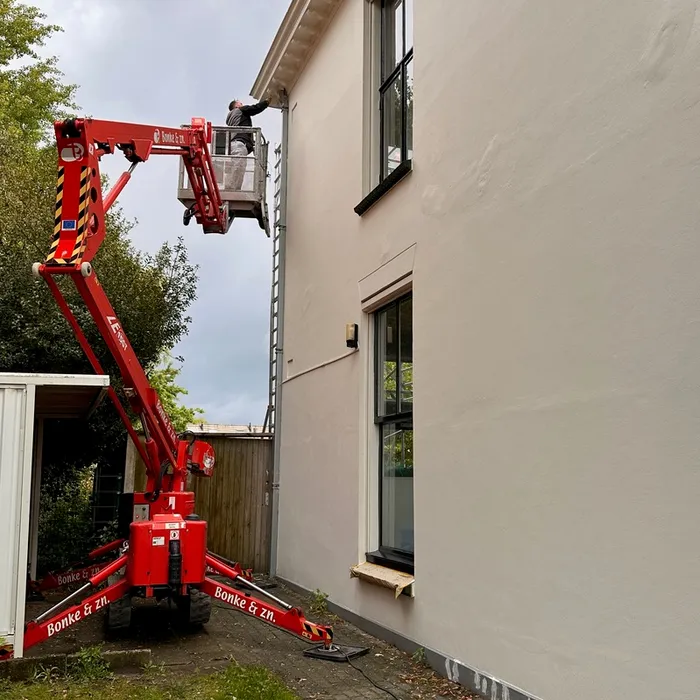 Schilder van Bonke & Zn. op hoogwerker bij buitenschilderwerk aan de gevel van villa Haaksbergerstraat in Enschede.