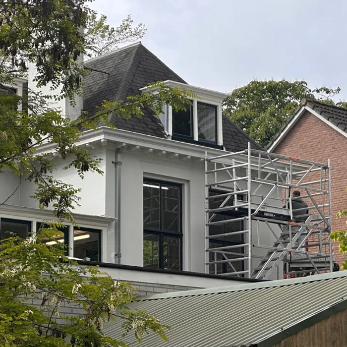 Wit geschilderde zijgevel van villa aan de Haaksbergerstraat in Enschede tijdens buitenschilderwerk door Schildersbedrijf Bonke & Zn., werk in uitvoering met steiger.