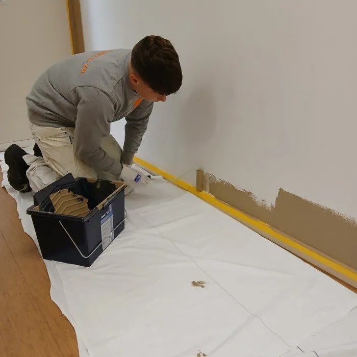 Leerling brengt eerste verflaag RAL 1019 aan op wand in afscheidskamer van de SEH Medisch Spectrum Twente.