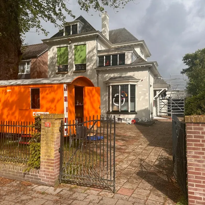 Voorgevel van Partou-locatie aan de Haaksbergerstraat in Enschede tijdens buitenschilderwerk door Schildersbedrijf Bonke & Zn., met bouwkeet op voorgrond.