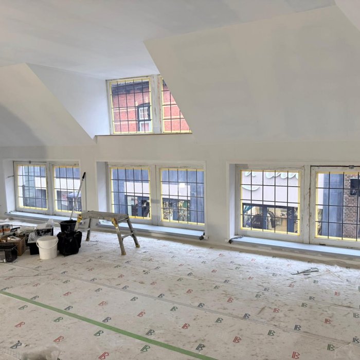 Binnenruimte tijdens renovatie aan de Grootestraat in Oldenzaal met voorbereid binnenstucwerk en afgedekte vloer voorafgaand aan schilderwerk.