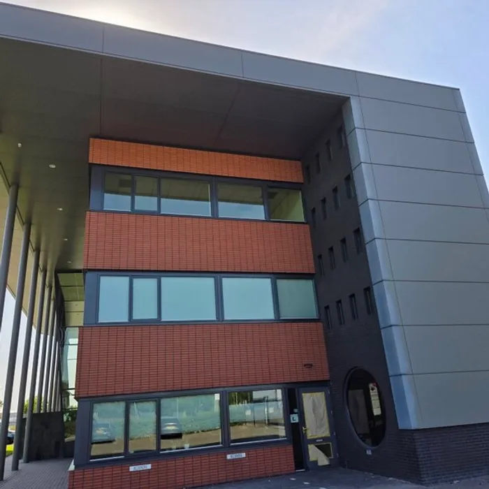 Hoekaanzicht van het pand met terracotta gevelstenen en geschilderde gevelplaten bij Wesselink Buunk